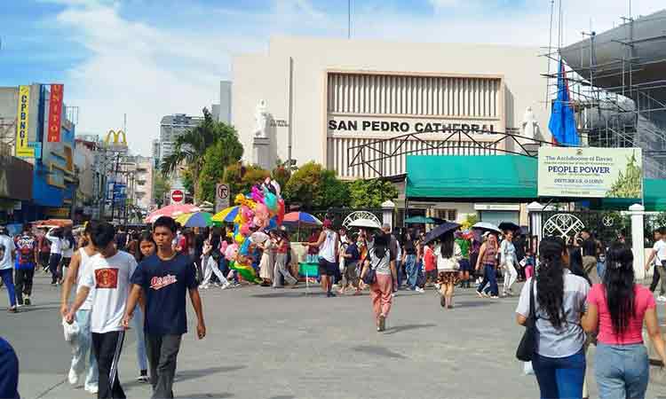 Crowds are filling San Pedro Street, with churchgoers visiting the nearby San Pedro Cathedral and others exploring the newly painted Davao City Hall.