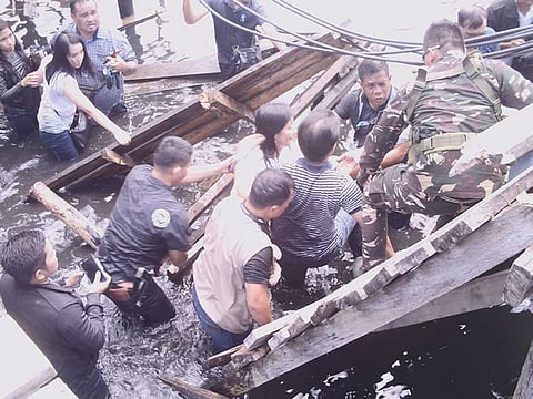ZAMBOANGA. A soldier of Task Force Zamboanga assists Mayor Maria Isabelle Climaco-Salazar (in white shirt) and Negros Occidental 3rd District Rep. Alfredo Abelardo Benitez (in striped shirt) after the wooden stilt-bridge they were on collapsed Thursday, April 26, 2018. (Bong Garcia)