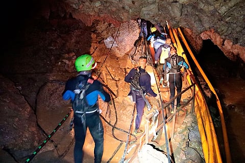In this undated photo released by Royal Thai Navy on Saturday, July 7, Thai rescue team members walk inside a cave where 12 boys and their soccer coach have been trapped since June 23, in Mae Sai, Chiang Rai province, northern Thailand. (Royal Thai Navy via AP)