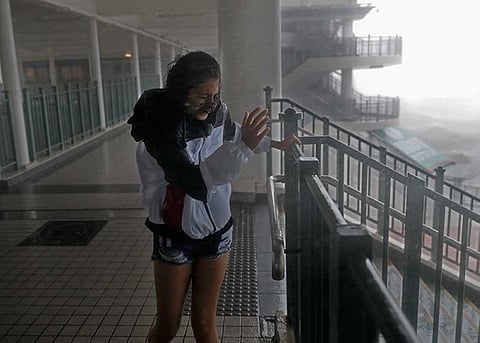HONGKONG. A girl stands against strong wind caused by Typhoon Mangkhut at a pier on the waterfront of Victoria Habour Hong Kong, Sunday, Sept. 16, 2018. Hong Kong and southern China hunkered down as strong winds and heavy rain from Typhoon Mangkhut lash the densely populated coast. (AP)