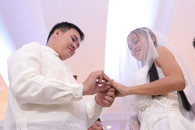WEARING OF THE RING. A groom puts a wedding ring on the finger of his bride, symbolizing their union in matrimony. (Mark Perandos)
