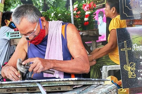 TOMBSTONED LIFE. Macky Tenebroso, 62, carves a tombstone outside Calamba Cemetery in Cebu City on Tuesday afternoon, Sept. 22, 2020. He is earning bread for his family by etching the names of the dead on marbles for decades now. Before the coronavirus disease 2019 pandemic hit Cebu City, Tenebroso said he had been earning P800 to P1,000 every day, and his income often doubled during Kalagkalag—Nov. 1 (All Saints' Day) and Nov. 2 (All Souls' Day). His wife supports him by selling flowers at the cemetery. With the closure of cemeteries from Oct. 29 to Nov. 4, the Tenebrosos have two options—to either stay at home or find other ways to put food on their table. (Amper Campaña)