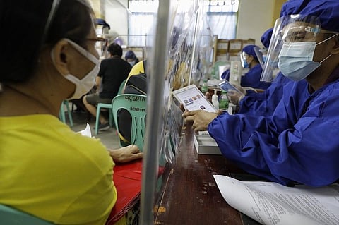 MANILA. A teacher wearing a protective suit to prevent the spread of the coronavirus demonstrates a student's electronic tablet to a woman as they prepare for online classes at the opening of school at the Dona Rosario High School in Quezon City on Thursday, Oct. 1, 2020. (AP)