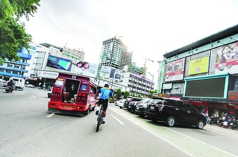 OCCUPIED. A cyclist passing by the Fuente Osmeña Rotunda in uptown Cebu City decides to ride it out on the fast lane rather than use the painted bike lane, which is partly blocked by parked vehicles. / Amper Campaña