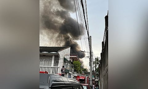LATE AFTERNOON BLAZE. Firefighters clump together at a walkway in Sitio Sto. Niño Laguna in Barangay Duljo Fatima, Cebu City as they prepare to penetrate the interior section of the area where a fire had hit at least 11 houses on Thursday afternoon, August 4, 2022. (Inset) As firefighters fight the flames, a fire volunteer from Basak San Nicolas is assisted by his colleagues after complaining of breathing difficulties while responding to the fire. (PHOTO BY AMPER CAMPAÑA)