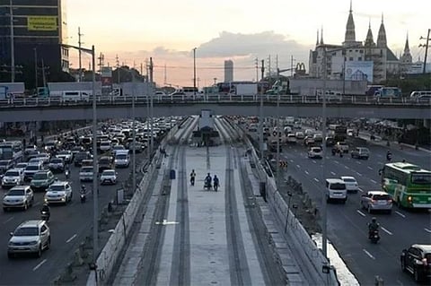 MANILA. Workers walk along a construction site of the MRT (Metro Rail Transit) while traffic builds up in Quezon City, Philippines as restrictions continue to ease due to a decline in Covid-19 cases in the country on December 3, 2021.
