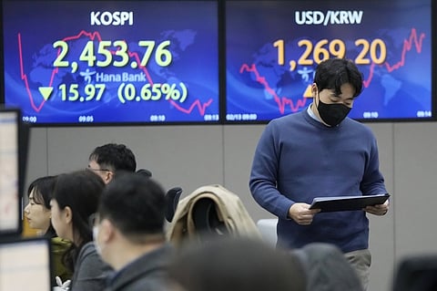 A currency trader passes by the screens showing the Korea Composite Stock Price Index (KOSPI), left, and the foreign exchange rate between U.S. dollar and South Korean won at the foreign exchange dealing room of the KEB Hana Bank headquarters in Seoul, South Korea, Monday, Feb. 13, 2023. Asian stock markets sank Monday ahead of a U.S. inflation update that traders worry might lead to more interest rate hikes. (AP Photo)