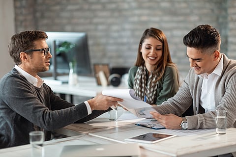 Young smiling couple signing a contract while having meeting wit