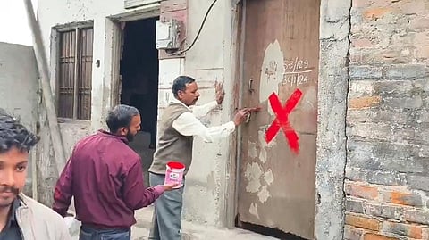 मकानों को तोड़ने के लिए रेड क्रॉस लगाते निगमकर्मी।