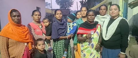 दुली की सहेलियां मौका देखकर कार्य स्थल से भागकर घर लौट गई। दुली मुर्मू अभी वहीं पर फंसी हैं। बेटी की फोटो दिखाती हुई दुली की मां (दायें से दूसरी) 