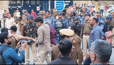 पुलिस का जबरन एक छात्र हाथ मरोड़ते लगभग तोड़ने का प्रयास करते हुए