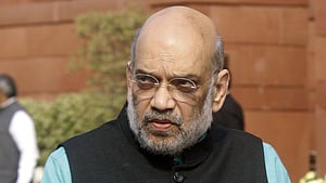 Amit Shah outside the parliament building in a blue shirt and black sleeveless jacket