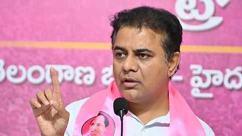 BRS leader KTR in a whire shirt wearing a pink scarf with a stern expression and a finger raised. 