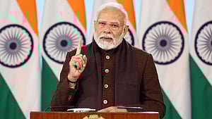 An image of PM Modi speaking at a podium. Indian flags in the backdrop