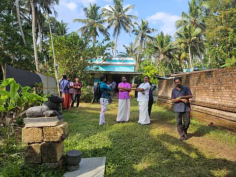 A group of people gathers around a statue in the yard, reflecting on the recent events surrounding Gopan Swami's death.