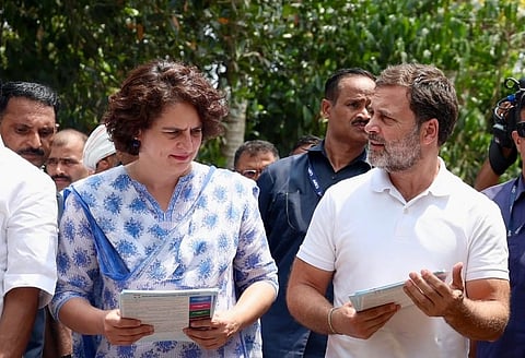 Rahul Gandhi and Priyanka Gandhi engaging in conversation, set against a neutral background. 