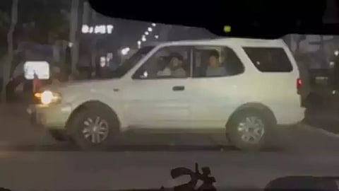 The image is a screegrab of the incident. A white SUV is parked across the road, blocking the way. There is flag belonging to the DMK party fixed on the SUV's front. Several men can be seen inside the SUV. It is night time.