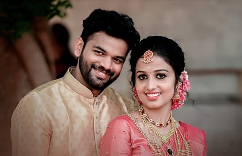 Prabhin and Vishnuja, a newlywed couple, smile joyfully in traditional Indian attire.