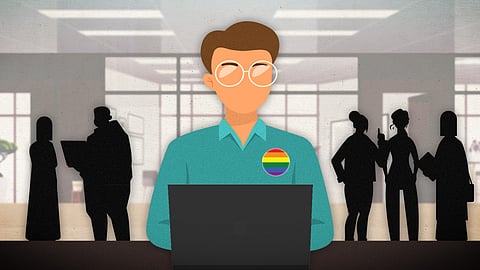 A person wearing a pride badge sitting in an office with figures standing behind him.