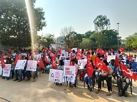 A group of people holding red flags and placards during a protest in Bengaluru.