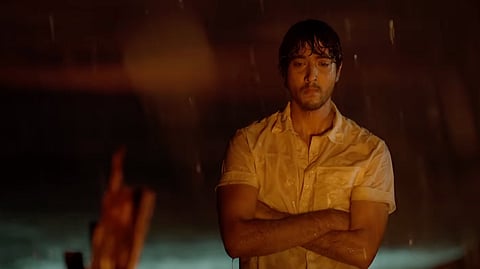 Sumukha in a scene from the film, facing the audience in a white shirt, looking distressed.