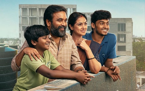 Poster of the Tamil film "Tourist Family" featuring actors Sasikumar, Simran, Mithun Jai Sankar, and Kamalesh smiling together on a balcony, with an urban cityscape in the background.