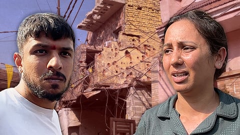 Two residents, a man and a woman in the foreground, destroyed homes in the background