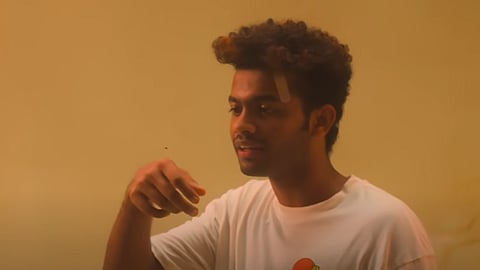 Actor Mathew Thomas in a white t shirt talking to a flying hovering above his right palm