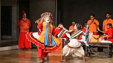 A Kattaikuttu play being performed on stage with two main actors in costume with musicians and instrumentalists in the background.