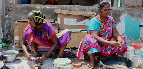 Two women in sarees clean fish squatting on the floor