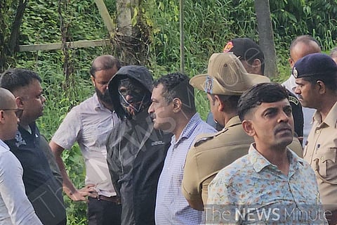 The whistleblower in a black jacket and mask along with officials