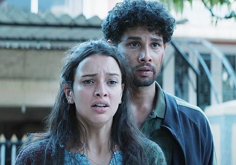Two young characters, a woman and a man with curly hair, stand close together looking distressed in a scene from Dhadak 2.