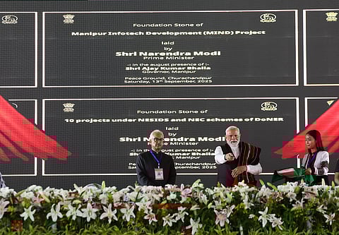 PM Modi on stage at a gathering held in Churachandpur, Manipur. The stage has a black screen in the background with the programme on it