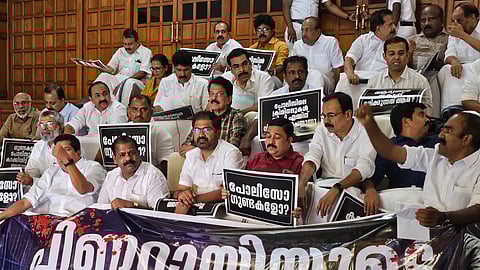 A group of opposition legislators in Kerala Assembly stage a protest inside the House, holding black placards with Malayalam slogans against police brutality.