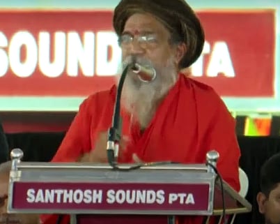 Shantananda Maharshi speaks at the Sabarimala Samrakshana Sangamam held in Pandalam. He is draped in a saffron robe and is wearing a black turban