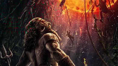 Rishabh Shetty's character Berme holding an axe and trishool and appearing to scream into the distance. A fiery hellscape in the background