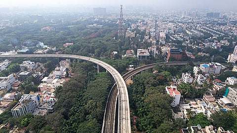 An aerial view of two metro lines going in opposite directions and the city's buildings in the background