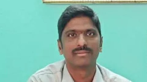 A close-up photograph of a man identified as Satish Kumar, possibly an Assistant Vigilance and Security Officer (AVSO) of TTD (Tirumala Tirupati Devasthanams), wearing a light-colored shirt against a teal/turquoise background. He has short, dark hair and a mustache.