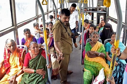 Women passengers seated in a bus, a male conductor is dispensing tickets