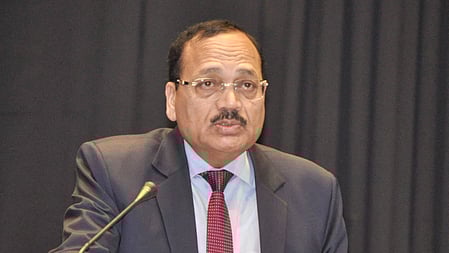 Justice Surya Kant in a black suit and maroon tie, speaking at a podium