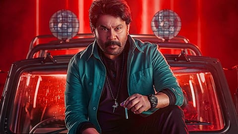 Dileep in Bha Bha Ba, seated on a jeep and looking at the audience.