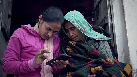 Two women operating a mobile phone