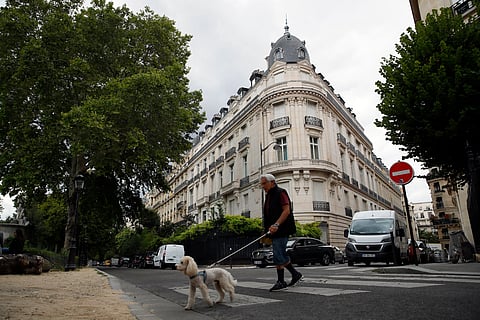 In this Aug.13, 2019 file photo, a man walks his dog next to an apartment building owned by Jeffrey Epstein in Paris. 