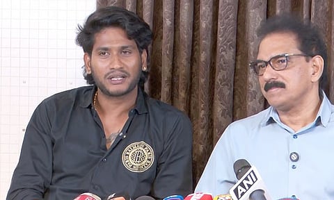 Akhil Marar and Sabu M Jacob seated side by side at a press meet, speaking to the media, with microphones placed in front of them against a curtained backdrop.