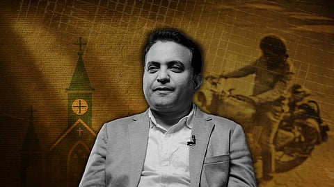 A monochrome portrait of Praveen Pagadala in a blazer and collared shirt wearing a lapel microphone, seated and looking slightly to the side. The background is a textured yellow-brown graphic showing silhouettes of church buildings with crosses on the left and a blurred image of a motorbike rider on the right, creating a dramatic, news-style composition.