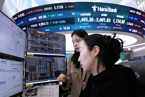 Currency traders watch monitors near a screen showing the Korea Composite Stock Price Index (KOSPI), top center, and the foreign exchange rate between U.S. dollar and South Korean won, top center left, at the foreign exchange dealing room of the Hana Bank headquarters in Seoul, South Korea, Tuesday, March 24, 2026.
