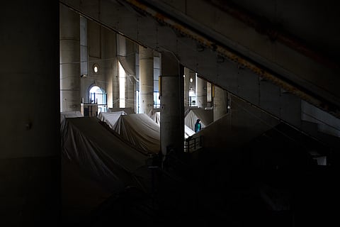 A displaced woman walks next to tents set up inside the Camille Chamoun Sports City Stadium, which has been turned into a shelter for people displaced by Israeli airstrikes in southern Lebanon, in Beirut, Lebanon, Monday, March 30, 2026. 