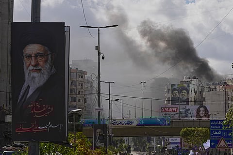 A portrait of Iran's late Supreme Leader Ayatollah Ali Khamenei, left, is seen, as smoke rises following an Israeli airstrike in Dahiyeh, Beirut's southern suburbs, Lebanon, Monday, March 30, 2026.
