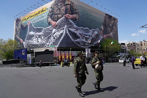 FILE - Two police officers walk in front of an anti-U.S. billboard depicting American aircraft being caught by Iranian armed forces in a fishing net beneath the words in Farsi, "The Strait of Hormuz will remain closed, The entire Persian Gulf is our hunting ground," in Tehran, Iran, Sunday, April 5, 2026. (AP Photo/Vahid Salemi, File)

