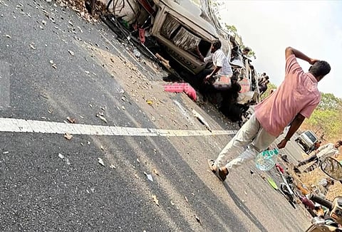 A severely damaged van lies on its side on a mountain road, with debris scattered around. Bystanders stand nearby, and one person appears to be assisting at the crash site along the Pollachi–Valparai ghat stretch.